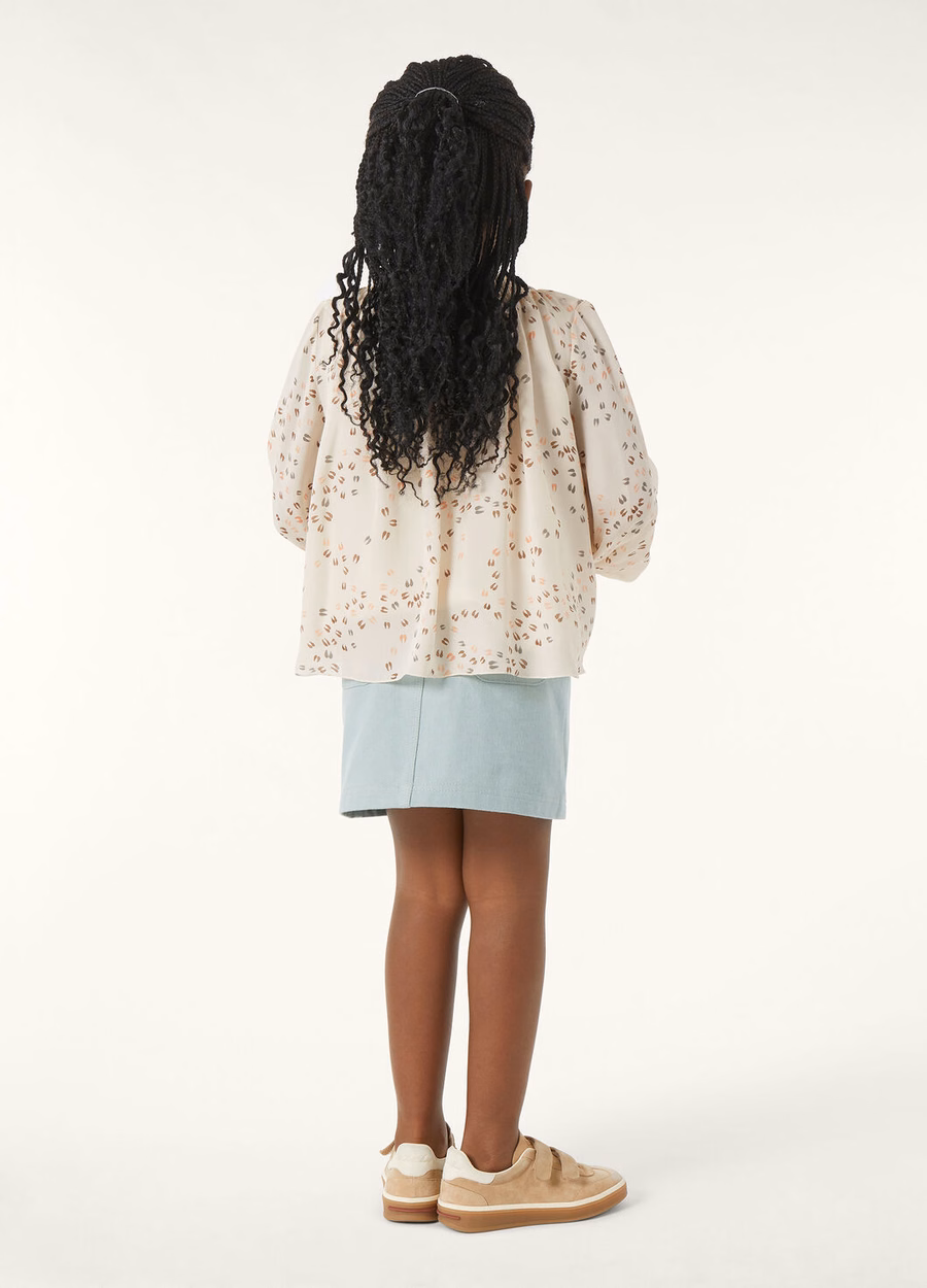 Falda infantil color arena, de mezclilla, con estampado de flores y cactus azul.